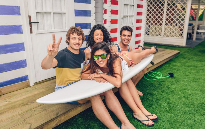 Young friends with woman siting on top of surfboard