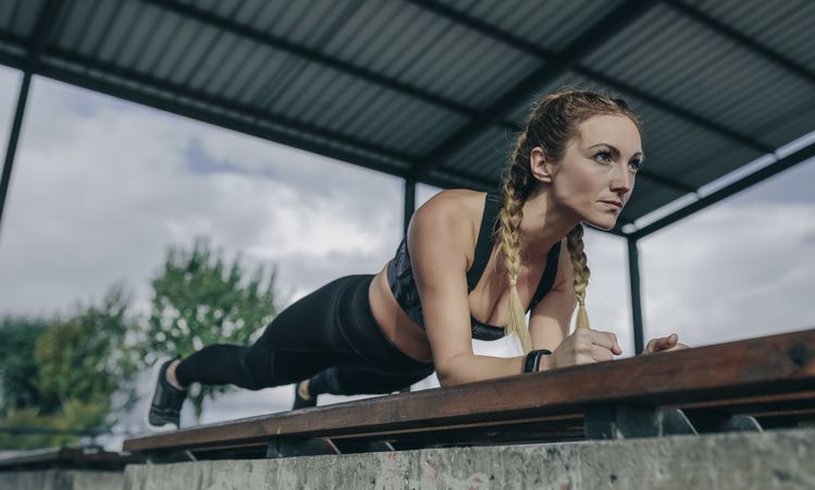 Sportswoman doing plank on a bench