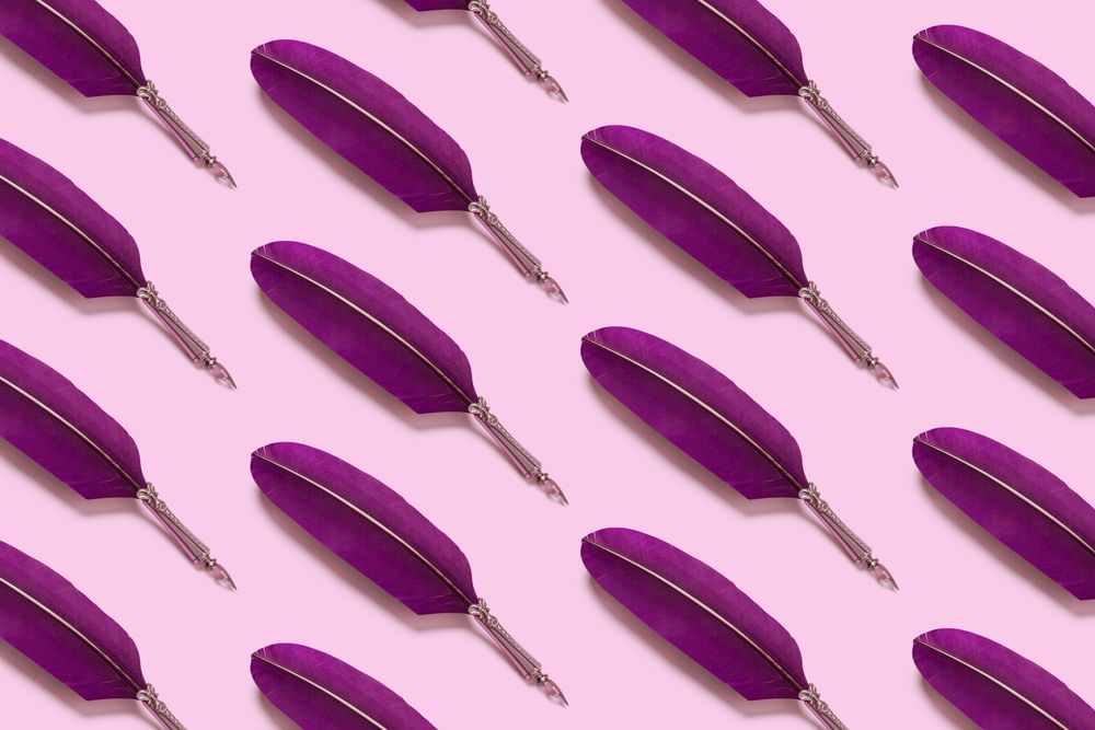 Purple quill pens on pink background
