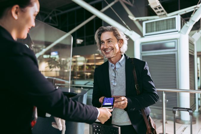 Smiling male traveler doing digital check in at airport terminal