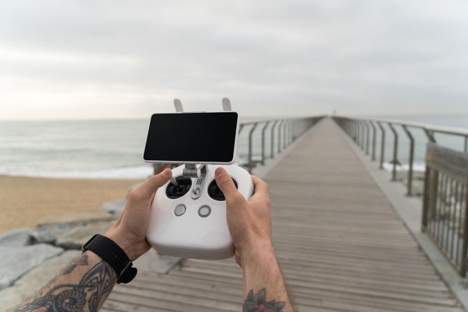 Man on boardwalk with remote for drone camera