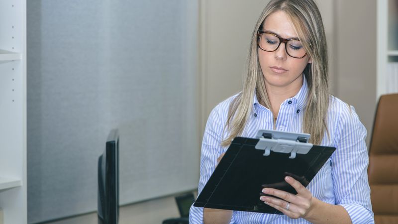 Woman taking notes with clipboard in office