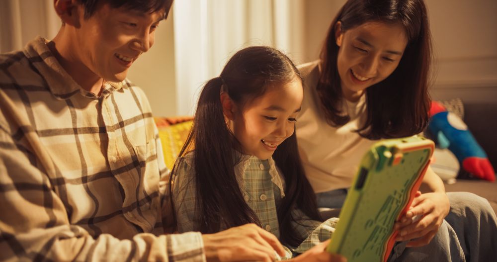 Korean Parents and Their Little Daughter Playing Games Together on a Digital Tablet Computer, Laughing and Having Fun