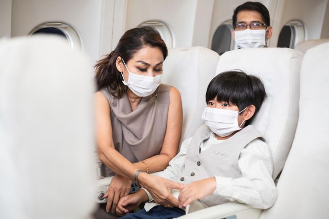 Woman helping her small child with seatbelt on airplane