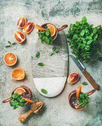 Top view of orange flavored cocktails garnished with fresh herbs