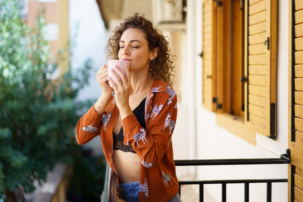 Woman enjoying fresh coffee on her balcony