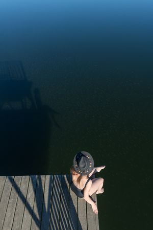 Young female sitting on pier on nature