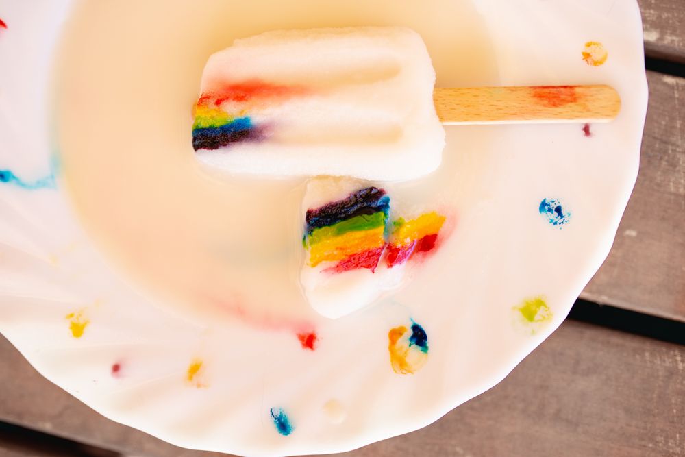Ice cream on wooden stick with rainbow symbol on decorated plate