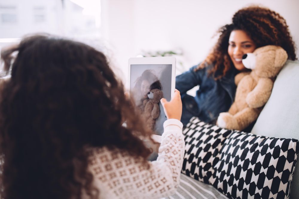 Little girl taking a photo of her mother with a tablet