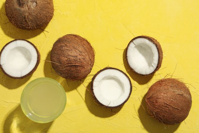 Coconut and water on yellow background, top view. Tropical fruit