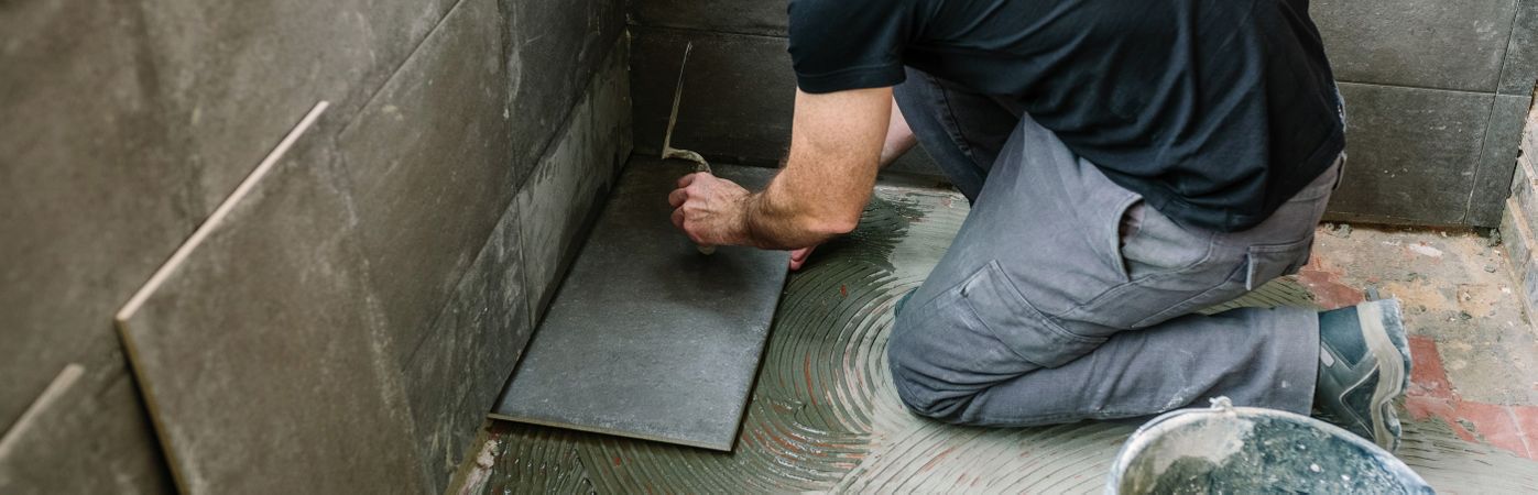 Workman laying tiles on a terrace