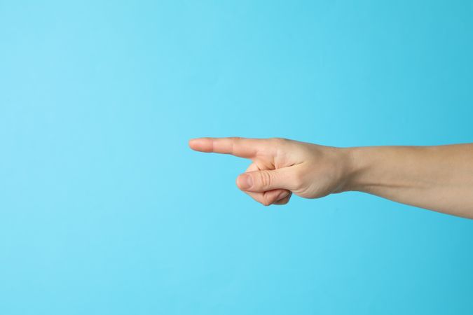 Female hand pointing on blue background, space for text