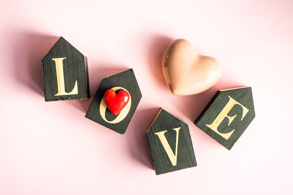 The word "love" on pastel pink table with heart ornaments