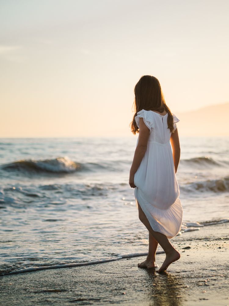 Adorable girl walking on seaside at sunset