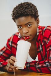 Stylish Black woman drinking from cup in cafe