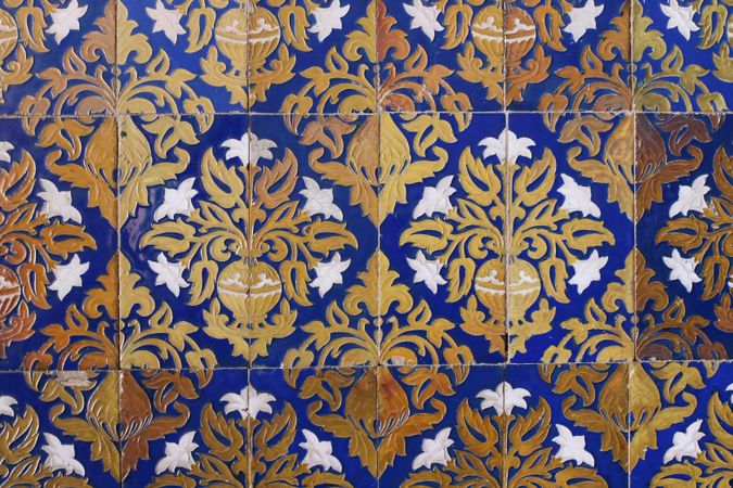 Detail of vintage Spanish ceramic tiles.Baroque styled pattern with lilies flowers, vases. Old blue azulejo facade with floral ornaments. Antique building detail. Artistic hand drawn decorative background