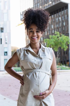 Smiling pregnant Black woman touching belly