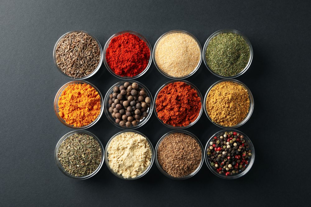 Rows of bowls of spices on dark table