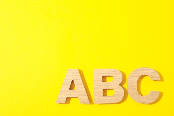 Wooden letters of English alphabet on color background, space for text