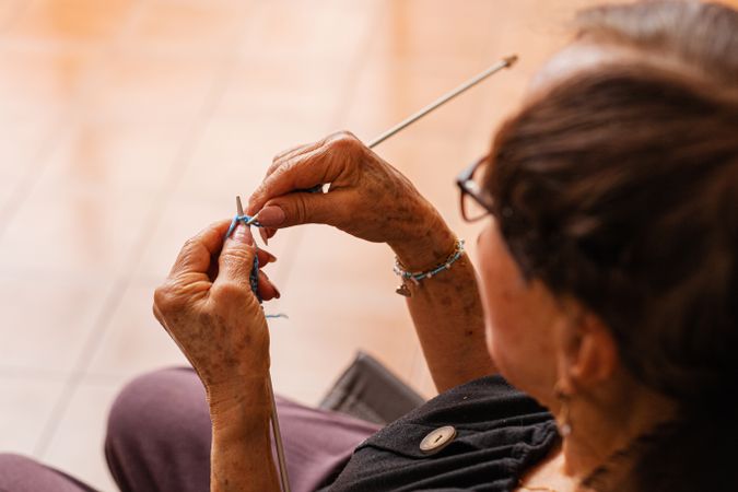Timeless textures. Older woman's hands weave tales in yarn.