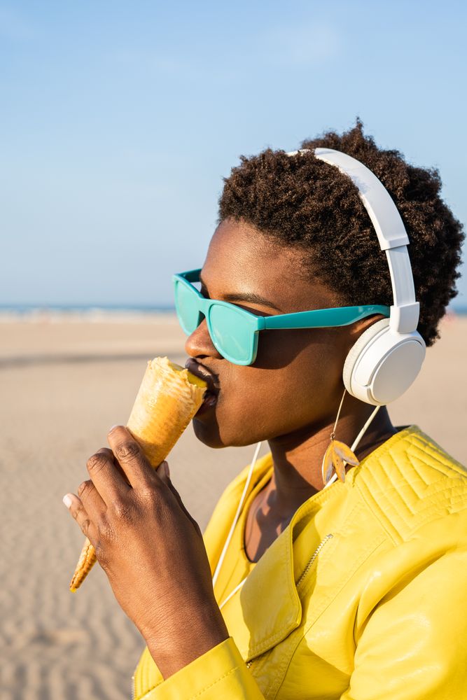 Cool female eating ice cream on beach