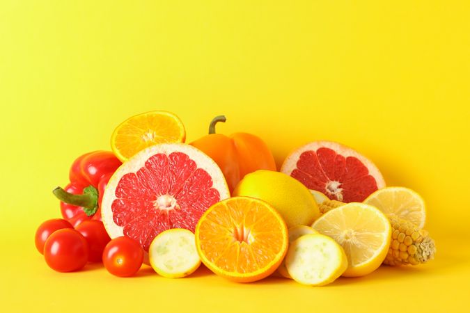 Different vegetables and fruits on yellow background, copy space
