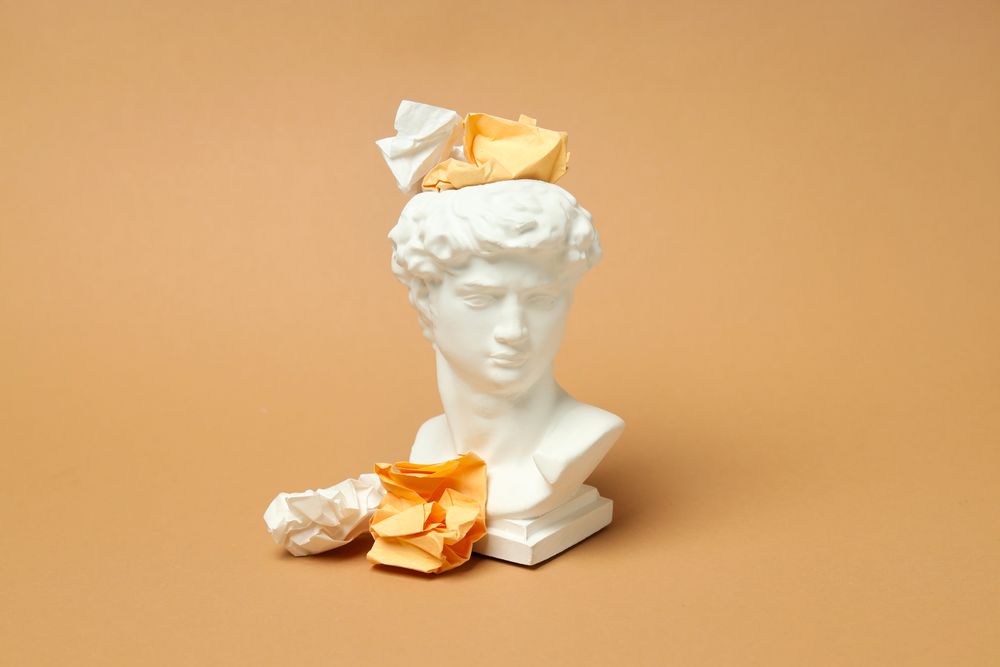 Marble bust with crumpled paper on brown background