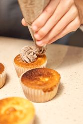 Crop person decorating cupcakes with cream