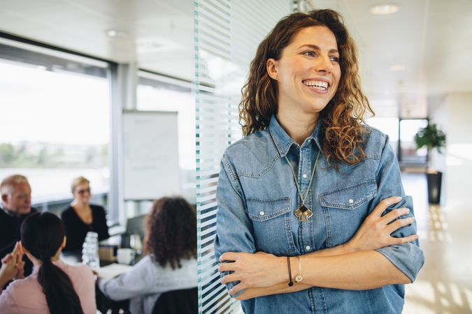 Smiling woman with coworkers in conference room having meeting