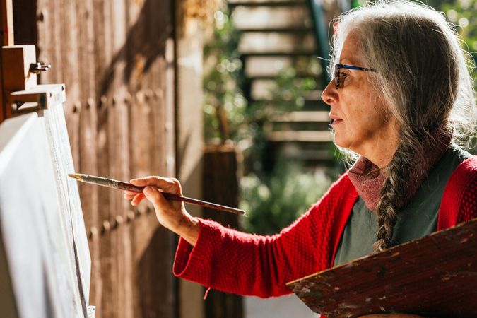 Mature woman painting on canvas in garden