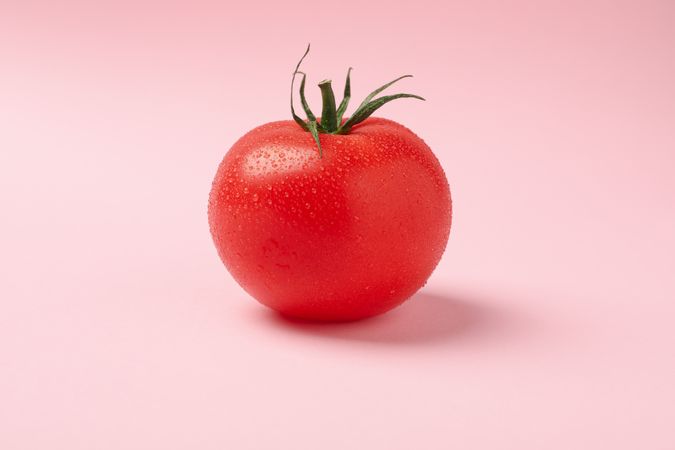 Fresh ripe tomato on pink background, close up