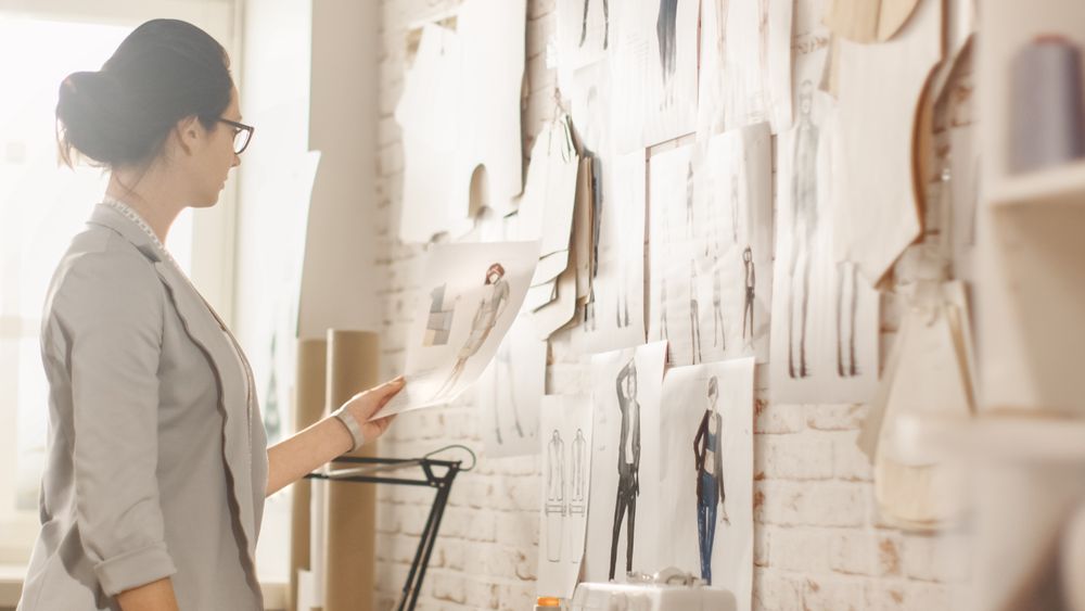 Female fashion, designer,  Choosing Sketches for Her Project and Pinning them to the Wall.