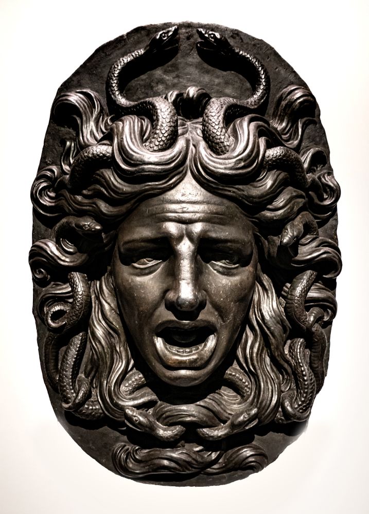 Bronze bas-relief. Medusa Gorgon. Decoration of an old wooden door.
