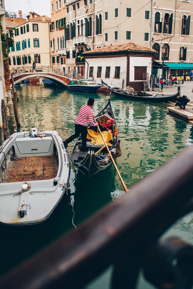 Man in boat floating in canal between buildings