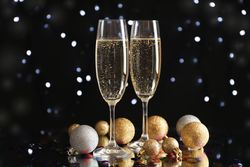 Christmas baubles and champagne glasses on blurred background, copy space