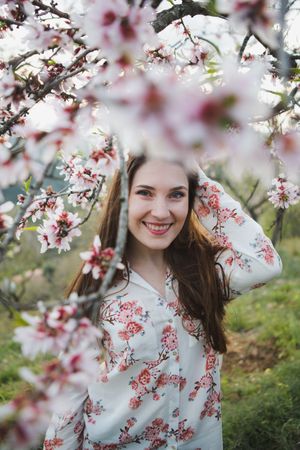 Young happy woman between trees in garden