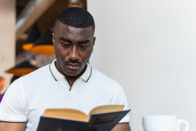 Serious male reading book in cafeteria