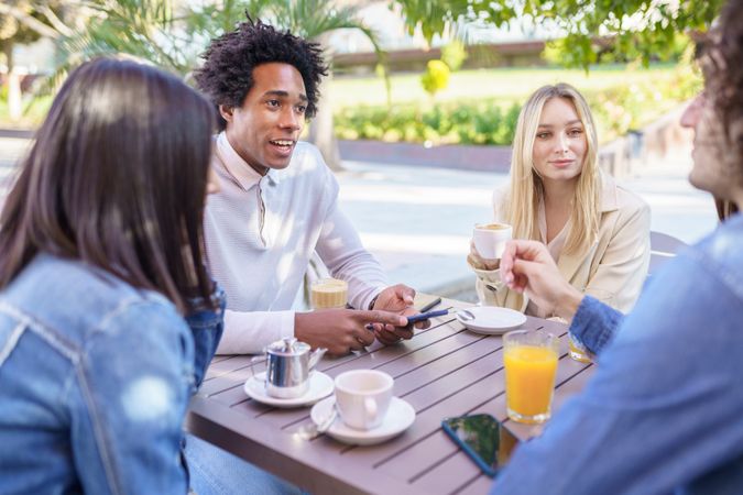 Multi-ethnic friends meeting up over coffee and juice outside