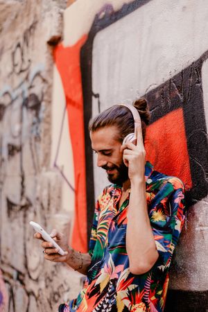 Smiling man listening to music and using smartphone