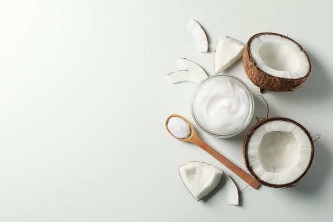 Coconut and cosmetics plain background, top view