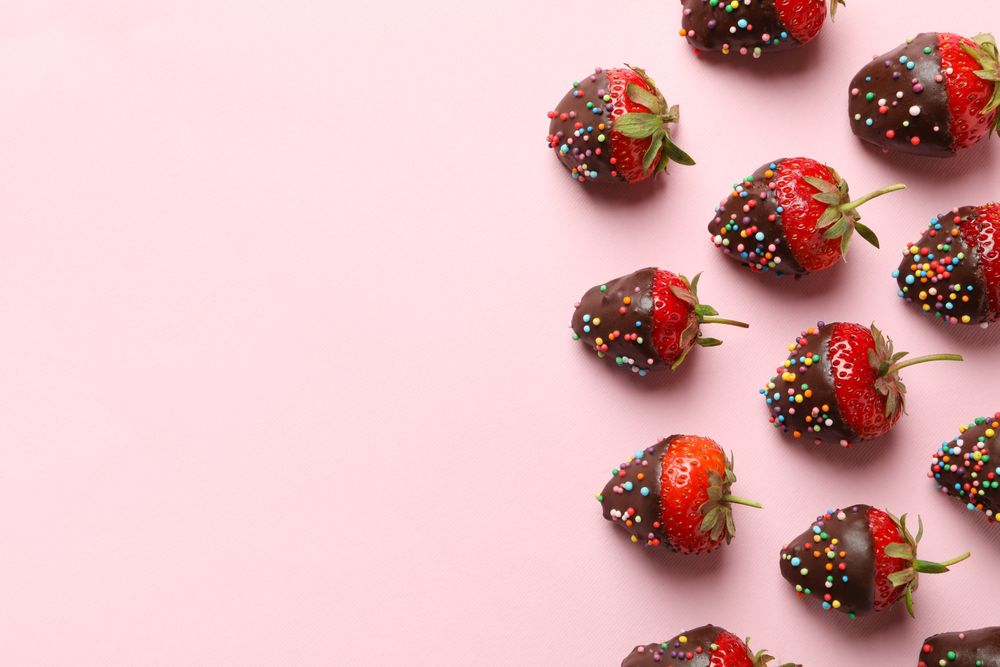 Chocolate fondue. Flat lay with strawberry in chocolate on pink background