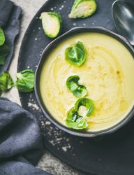 Bowl of Brussels sprout soup, on dark plate, vertical composition, close up