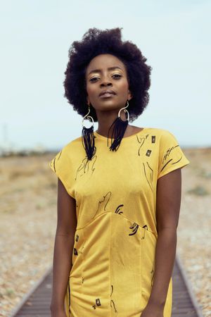 Portrait of young woman in yellow dress standing in desert