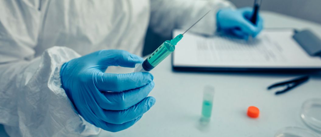 Scientist hand holding a syringe with virus vaccine