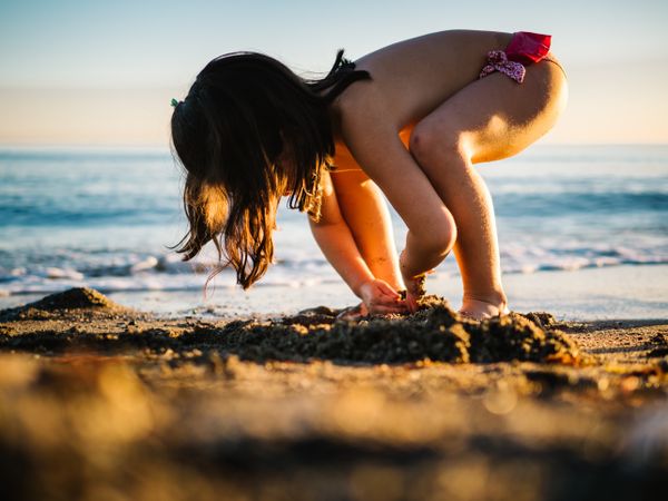 Cute little girl playing with sand at beach