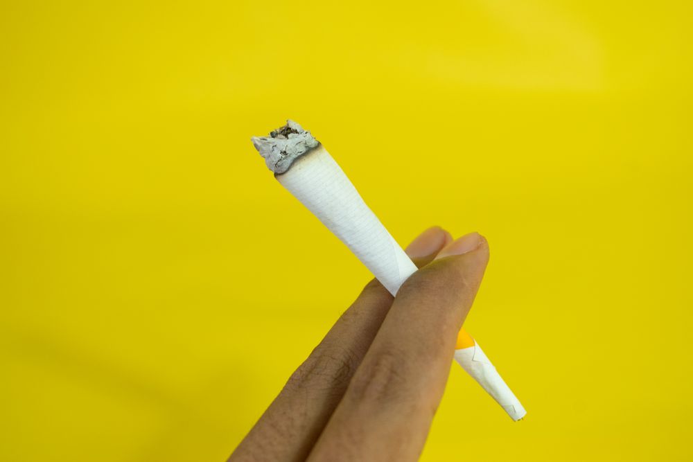 Hand holding lit cigarette
