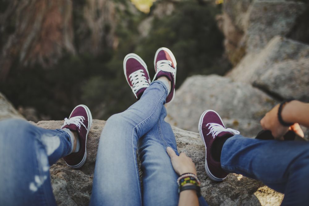 Casual couple resting together while sitting on high cliff