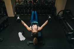Woman lifting dumbbells on bench