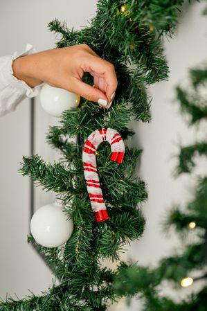 Christmas ornament being put on the Christmas tree by an unrecognizable woman