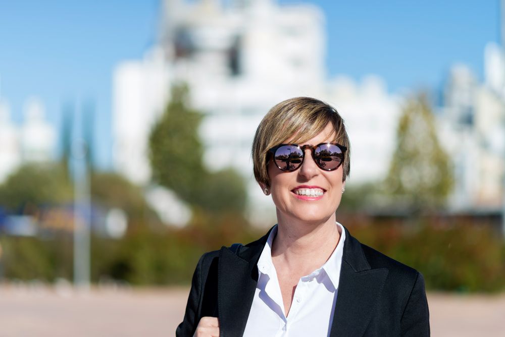 Smiling woman in sunglasses standing in city square